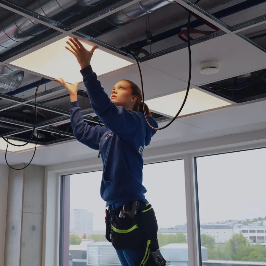 Elektriker fra Elteam i Trøndelag, en del av Nimlas, installerer et lysarmatur i et kontorlokale